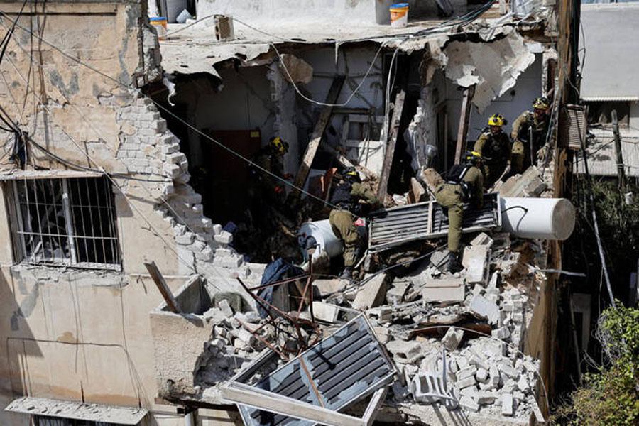 Israeli soldiers inspect the site of a damaged building following barrages of Iranian missiles, amid the U.S.-Israeli conflict with Iran, in Tel Aviv, Israel, March 22, 2026. REUTERS/Amir Cohen